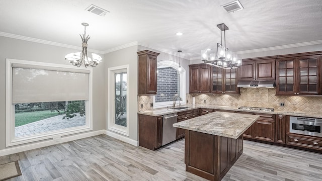 kitchen with an inviting chandelier, a sink, under cabinet range hood, and visible vents