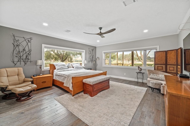 bedroom with visible vents, crown molding, and wood finished floors