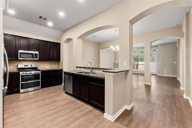 14356 N Summerchase Cir, Willis, TX 77318 - kitchen featuring visible vents, light wood-type flooring, dark stone counters, a sink, and appliances with stainless steel finishes