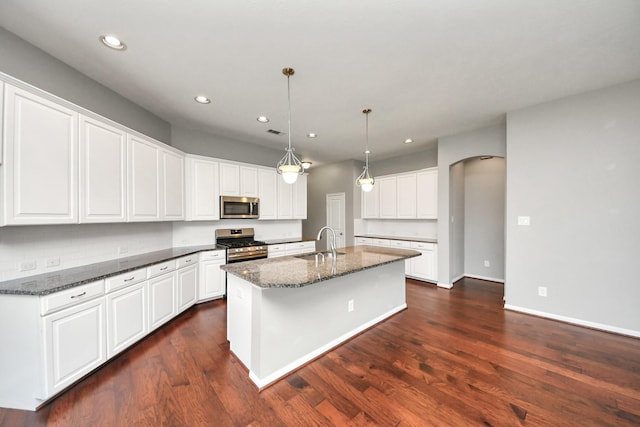 12427 Point Arbor Ct, Tomball, TX 77377 - kitchen with stainless steel appliances, recessed lighting, white cabinetry, arched walkways, and a kitchen island with sink