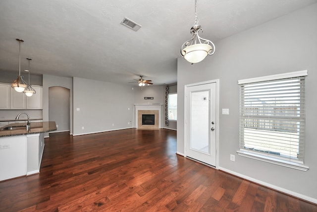 12427 Point Arbor Ct, Tomball, TX 77377 - unfurnished living room with a sink, ceiling fan, arched walkways, a fireplace, and visible vents