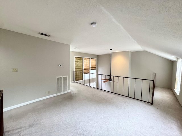 2323 Augusta Dr Unit 36, Houston, TX 77057 - spare room featuring a textured ceiling, carpet flooring, healthy amount of natural light, a smoke detector, and vaulted ceiling