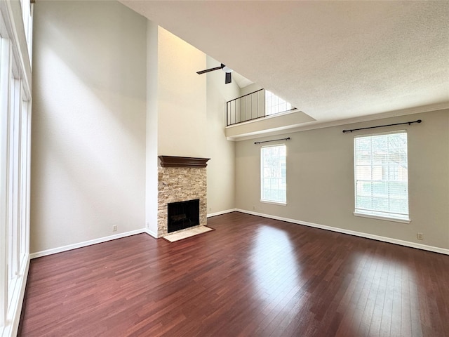 2323 Augusta Dr Unit 36, Houston, TX 77057 - unfurnished living room with dark wood-type flooring, a stone fireplace, and a towering ceiling