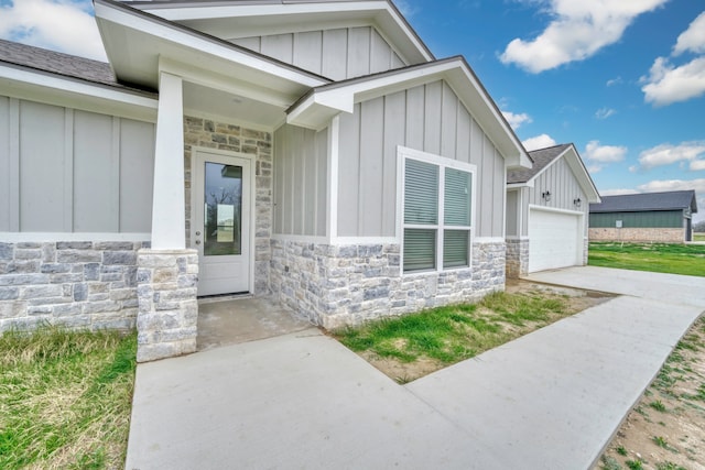 view of exterior entry featuring stone siding, board and batten siding, and concrete driveway