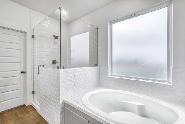 full bath with a bath, wood finished floors, and a stall shower