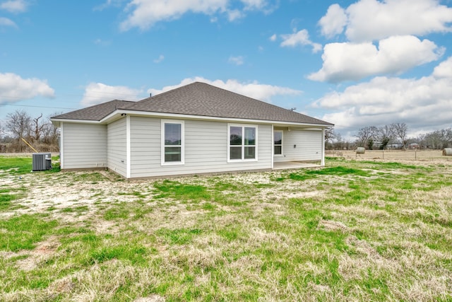 back of house featuring a patio area, central AC unit, a shingled roof, and a lawn