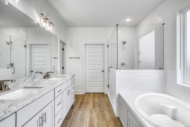 bathroom with a stall shower, wood finished floors, a garden tub, and a sink