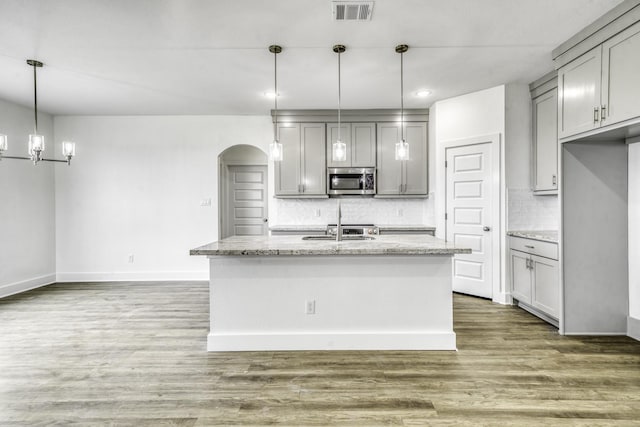 kitchen with stainless steel microwave, visible vents, wood finished floors, and gray cabinets