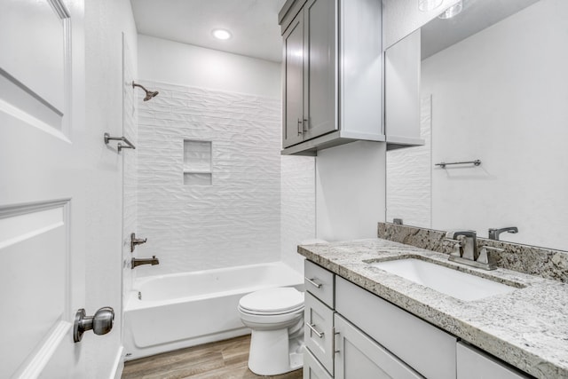 bathroom with toilet, vanity,  shower combination, and wood finished floors