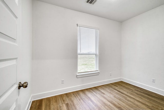 spare room with visible vents, wood finished floors, and baseboards