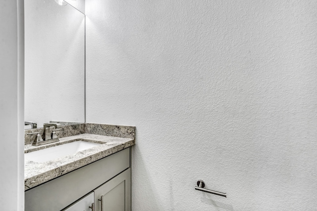bathroom with vanity and a textured wall