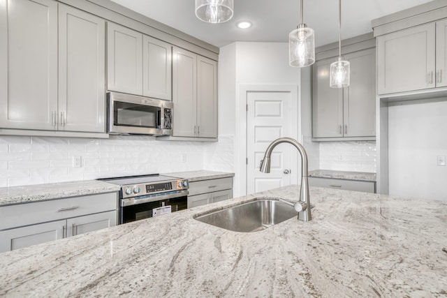 kitchen featuring a sink, stainless steel appliances, light stone countertops, and gray cabinets