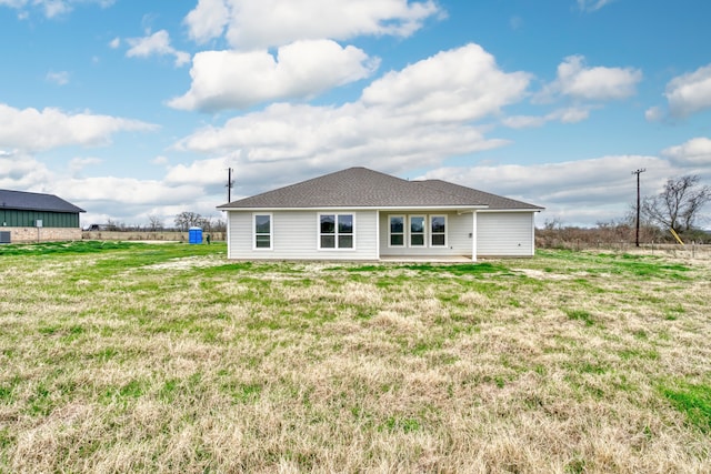 back of property featuring a lawn and a shingled roof