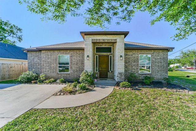 view of front of property featuring brick siding, stone siding, a front yard, and fence