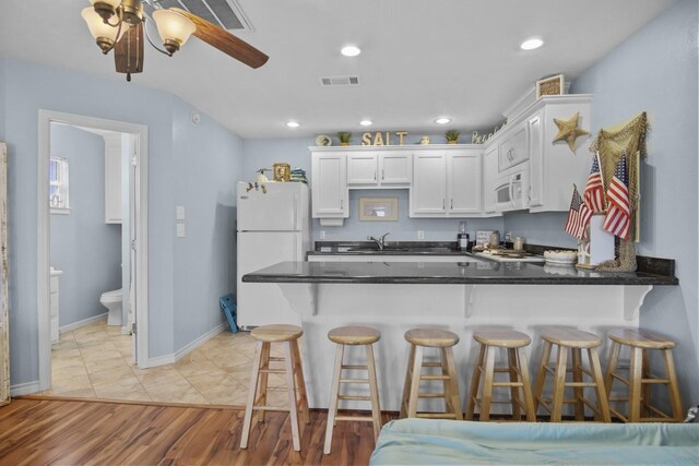 979 Sea Spray Dr, Crystal Beach, TX 77650 - kitchen with visible vents, white appliances, a peninsula, and white cabinetry