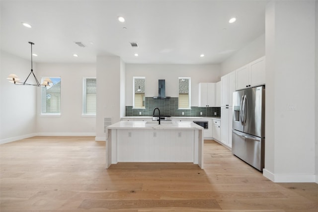 kitchen with stainless steel fridge, wall chimney exhaust hood, a chandelier, and white cabinetry