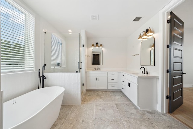 bathroom with double vanity, visible vents, a stall shower, a sink, and a soaking tub
