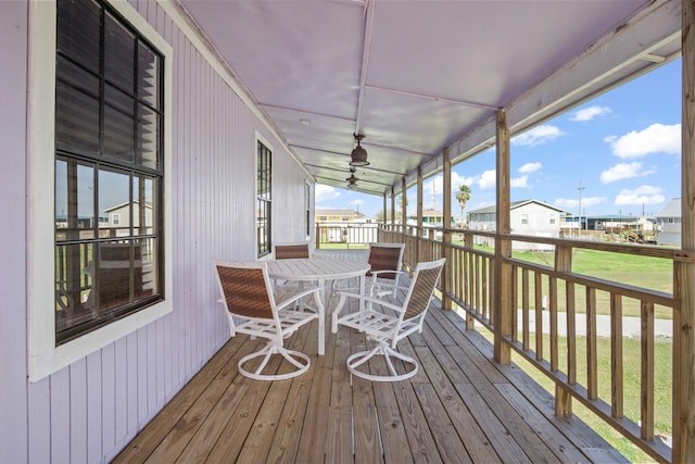 deck with outdoor dining area, a residential view, a yard, and a ceiling fan