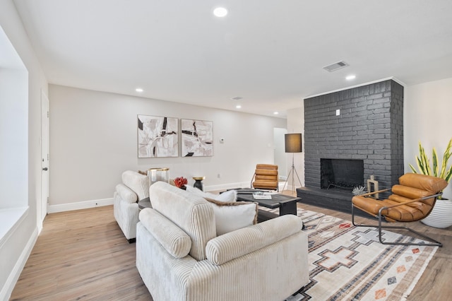 living area with visible vents, baseboards, recessed lighting, a fireplace, and light wood-style floors