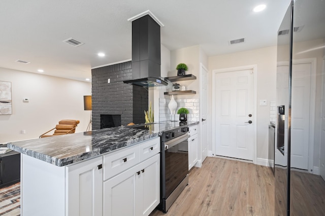 kitchen featuring visible vents, a peninsula, island exhaust hood, and open shelves