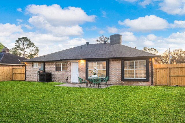 back of property featuring brick siding, a patio area, a fenced backyard, and a lawn