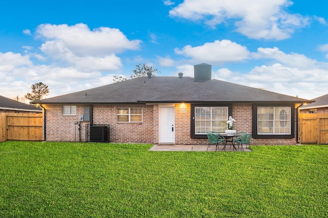 back of house featuring brick siding, a patio, a fenced backyard, and a lawn