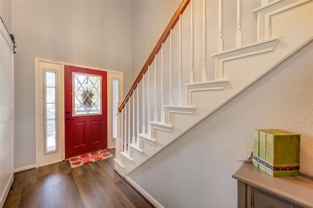 foyer entrance with a towering ceiling, stairs, baseboards, and dark wood finished floors