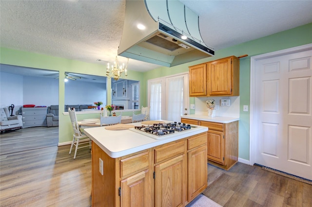 kitchen with under cabinet range hood, light countertops, a kitchen island, white gas stovetop, and light wood finished floors