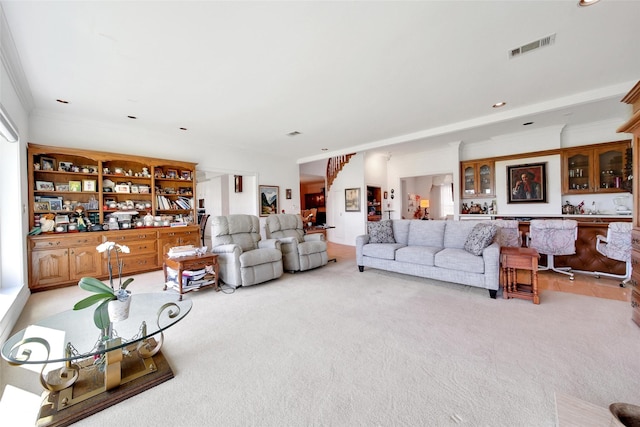 living area with visible vents, ornamental molding, and light carpet