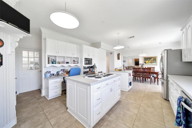 kitchen featuring white electric stovetop, freestanding refrigerator, a kitchen island, light countertops, and decorative light fixtures