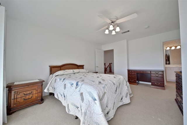 bedroom with a ceiling fan, visible vents, light carpet, and ensuite bath