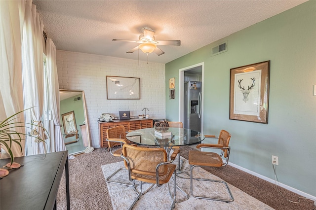 carpeted dining area featuring visible vents, baseboards, a textured ceiling, and ceiling fan