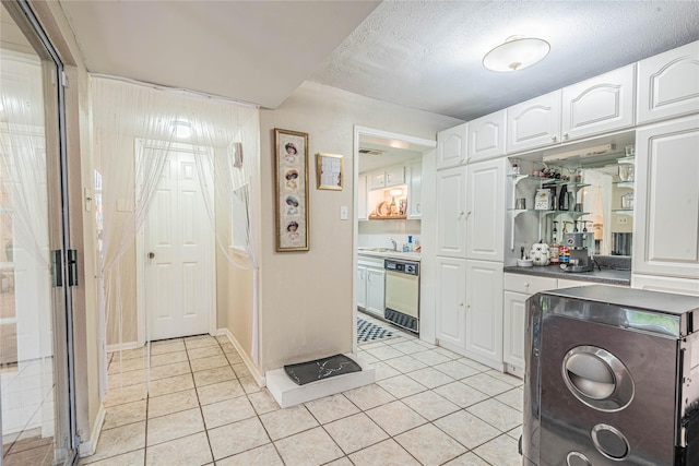 kitchen featuring dishwasher, light tile patterned flooring, white cabinetry, and a textured ceiling