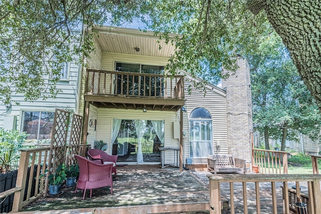 rear view of property featuring a balcony and a chimney