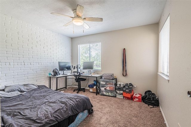 carpeted bedroom with baseboards, a textured ceiling, brick wall, and a ceiling fan