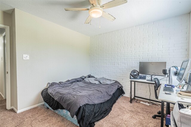carpeted bedroom featuring a textured ceiling, baseboards, brick wall, and ceiling fan
