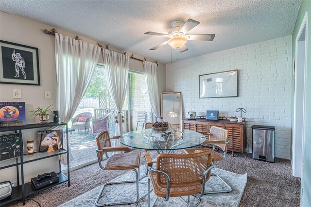 carpeted dining area with a textured ceiling, brick wall, and ceiling fan