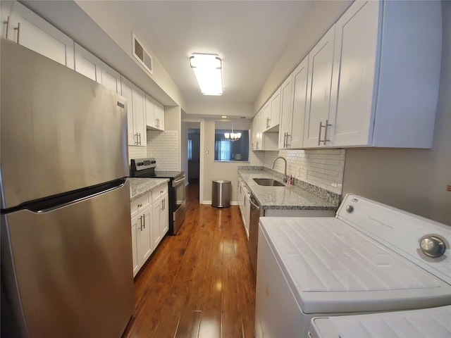kitchen with dark wood-type flooring, a sink, light stone counters, washer / clothes dryer, and stainless steel appliances