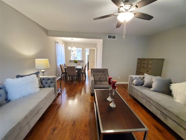 living area featuring visible vents, ceiling fan with notable chandelier, dark wood-type flooring, and baseboards