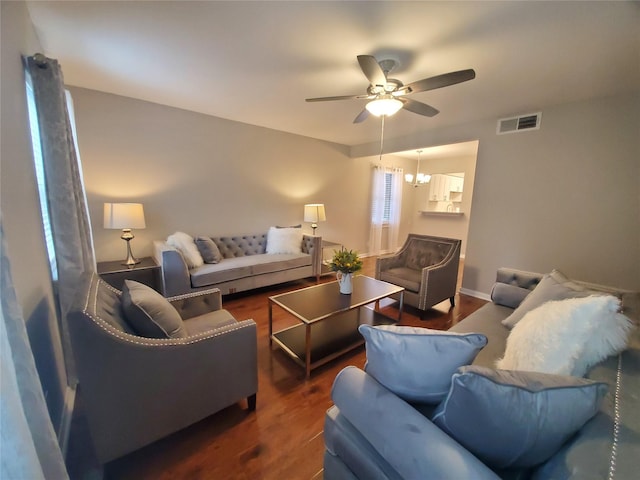 living area with visible vents, baseboards, dark wood-type flooring, and a ceiling fan