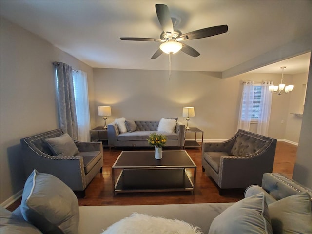 living room featuring wood finished floors, ceiling fan with notable chandelier, and baseboards