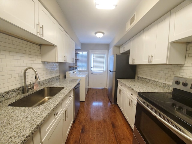 kitchen featuring dark wood finished floors, a sink, stainless steel appliances, white cabinetry, and washing machine and dryer