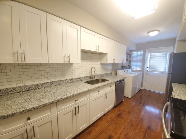 kitchen with a sink, dark wood-type flooring, decorative backsplash, stainless steel appliances, and separate washer and dryer
