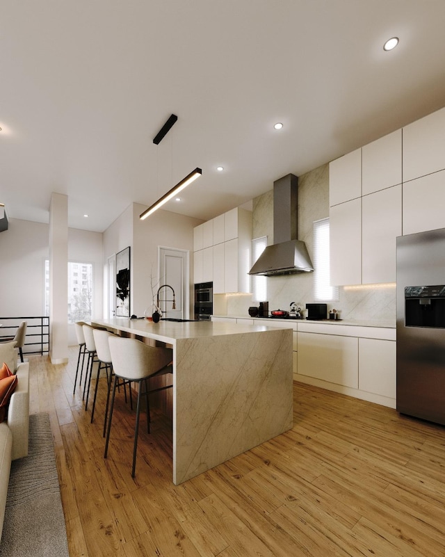 5505 Hershe St, Houston, TX 77020 - kitchen featuring appliances with stainless steel finishes, wall chimney range hood, modern cabinets, light wood-style floors, and a spacious island