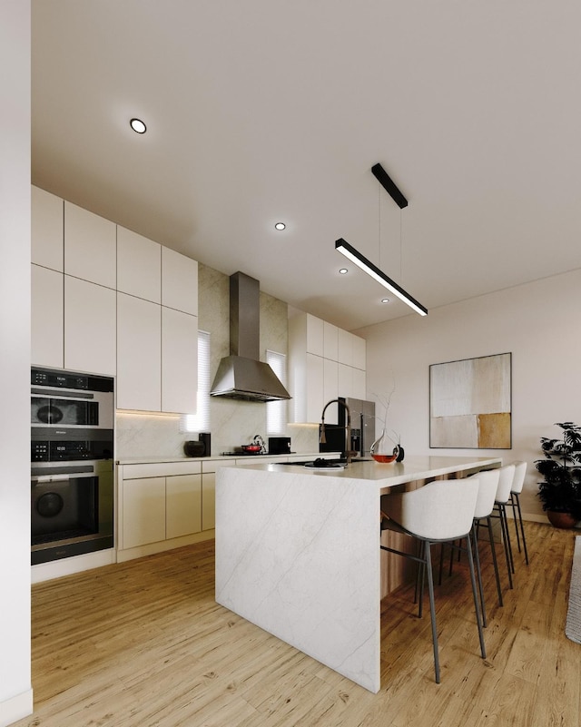 5505 Hershe St, Houston, TX 77020 - kitchen with wall chimney range hood, light wood finished floors, light countertops, modern cabinets, and an island with sink