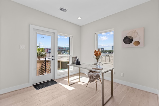 home office with light wood finished floors, visible vents, a healthy amount of sunlight, and baseboards