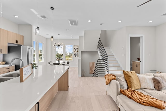 kitchen featuring visible vents, modern cabinets, a sink, open floor plan, and light wood finished floors