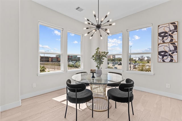 dining space featuring visible vents, a healthy amount of sunlight, light wood-style floors, and an inviting chandelier