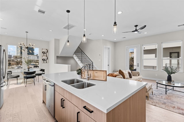 kitchen with visible vents, a sink, open floor plan, light wood-style floors, and appliances with stainless steel finishes