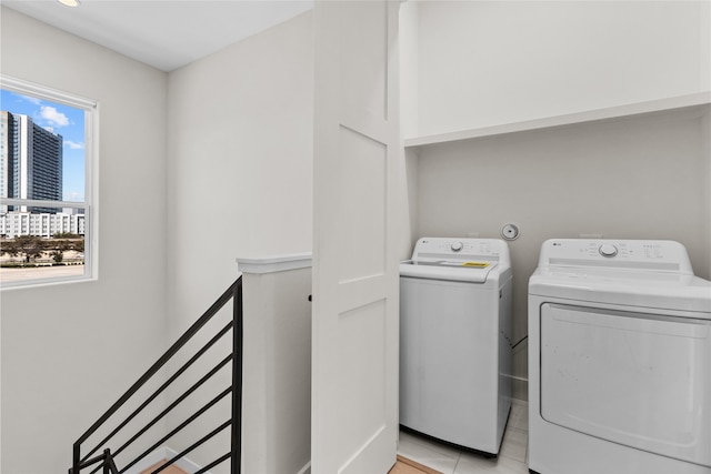 laundry room featuring light tile patterned floors, a view of city, washing machine and dryer, and laundry area